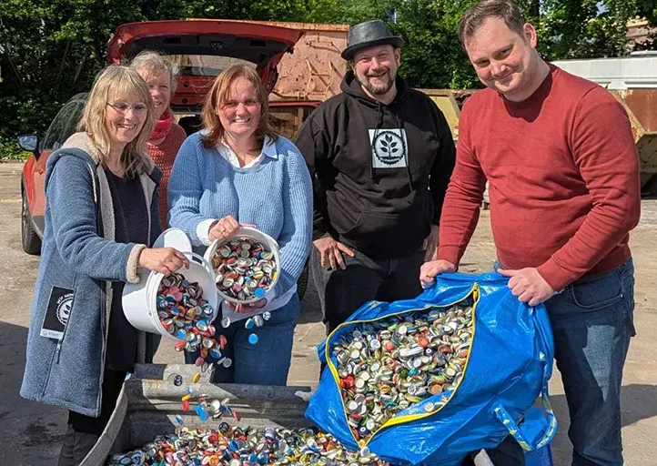 Gruppenfoto mit dem Team Klimadeckel, das eimerweise Kronkorken zusammenschüttet, um diese zu recyclen
